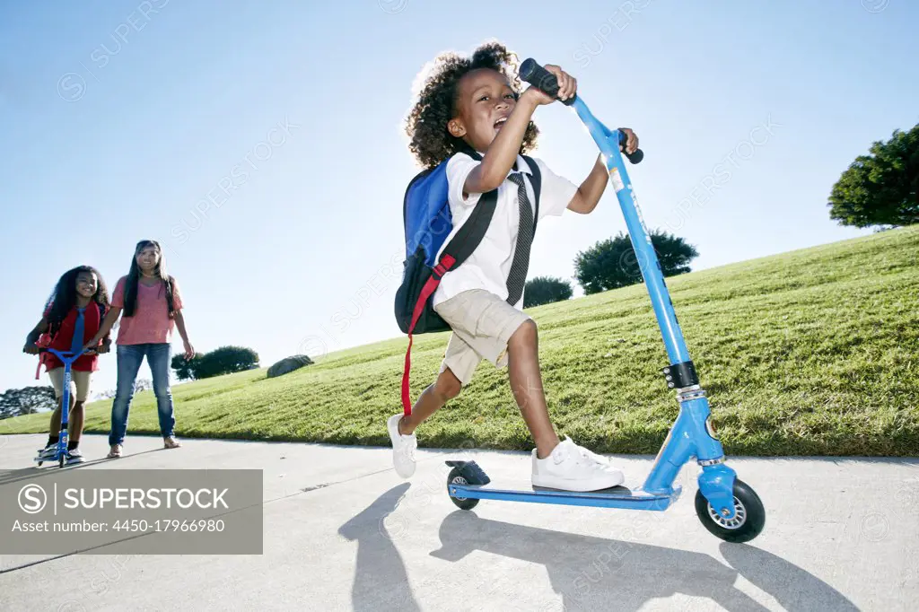 Six year old boy on a scooter, followed by his sister