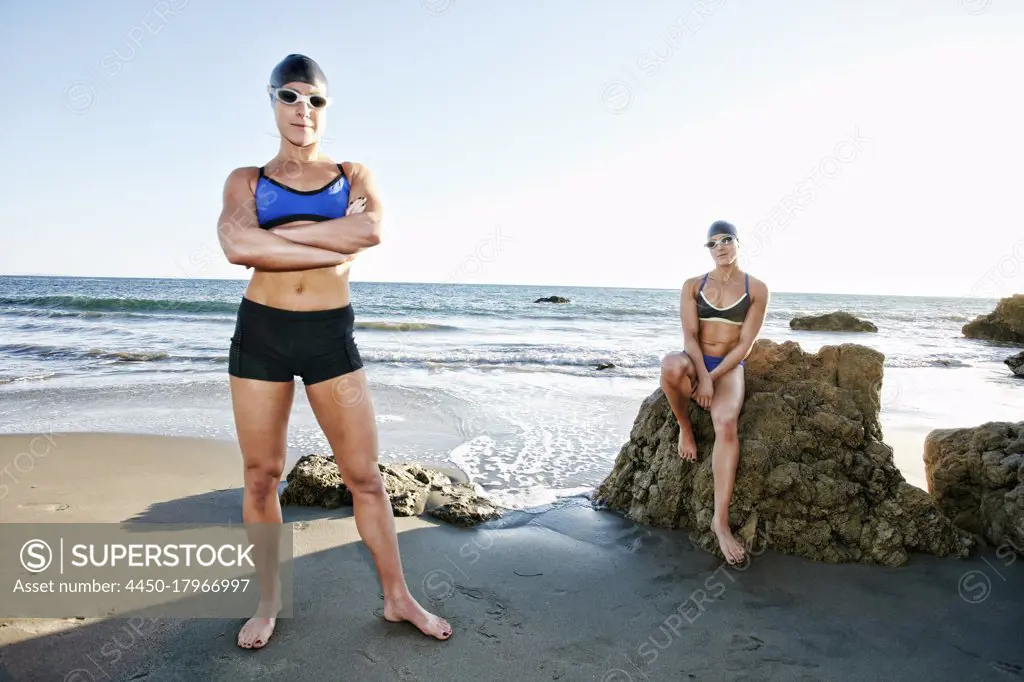 Two sisters, triathletes in training in swimwear, swimhats and goggles. 