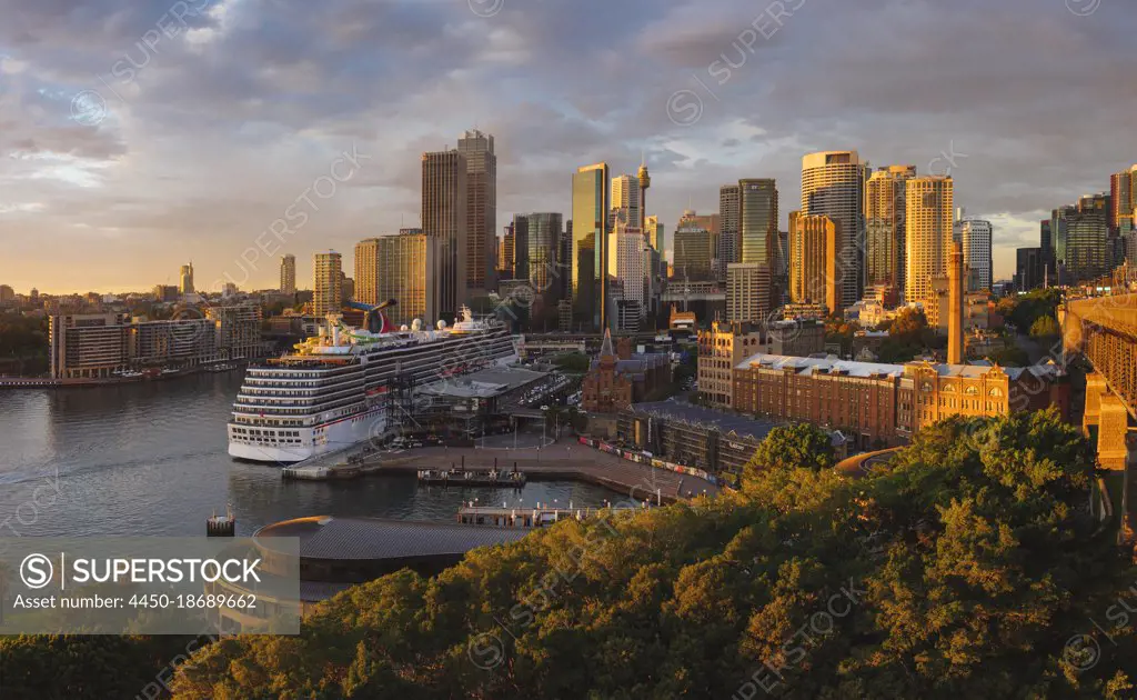 Cruise ship docked in Sydney Harbour with skyscrapers behind.