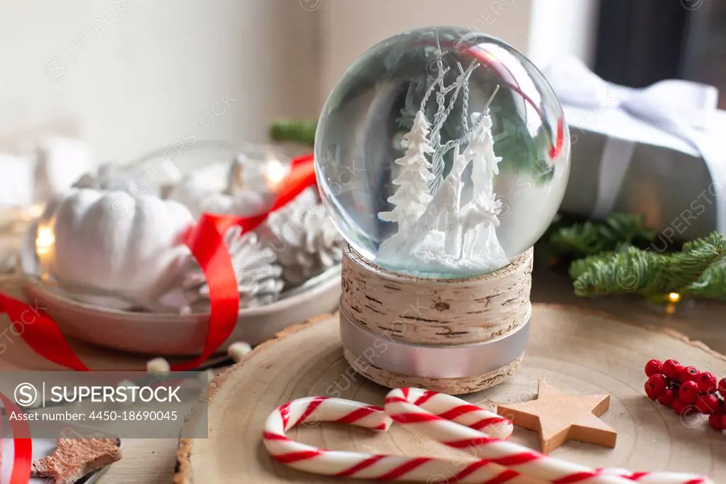 Christmas decorations, a snow globe and presents and star shaped biscuits. 