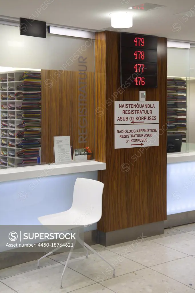 Waiting area and reception desk at a modern hospital, with signs and electronic display