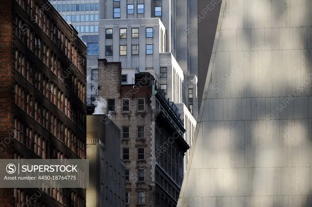 Buildings in New York City, view from below, historic and modern architecture, shadows and sunlight