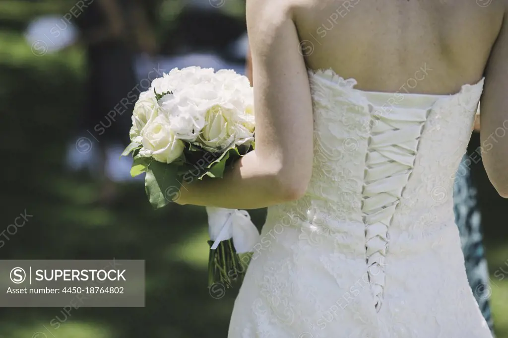 A bride in a fitted bodice, white dress with lacings across the fitted back panels. 