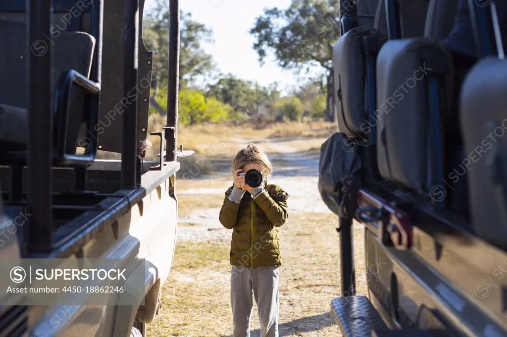 young boy with camera on safari, Okavango Delta, Botswana