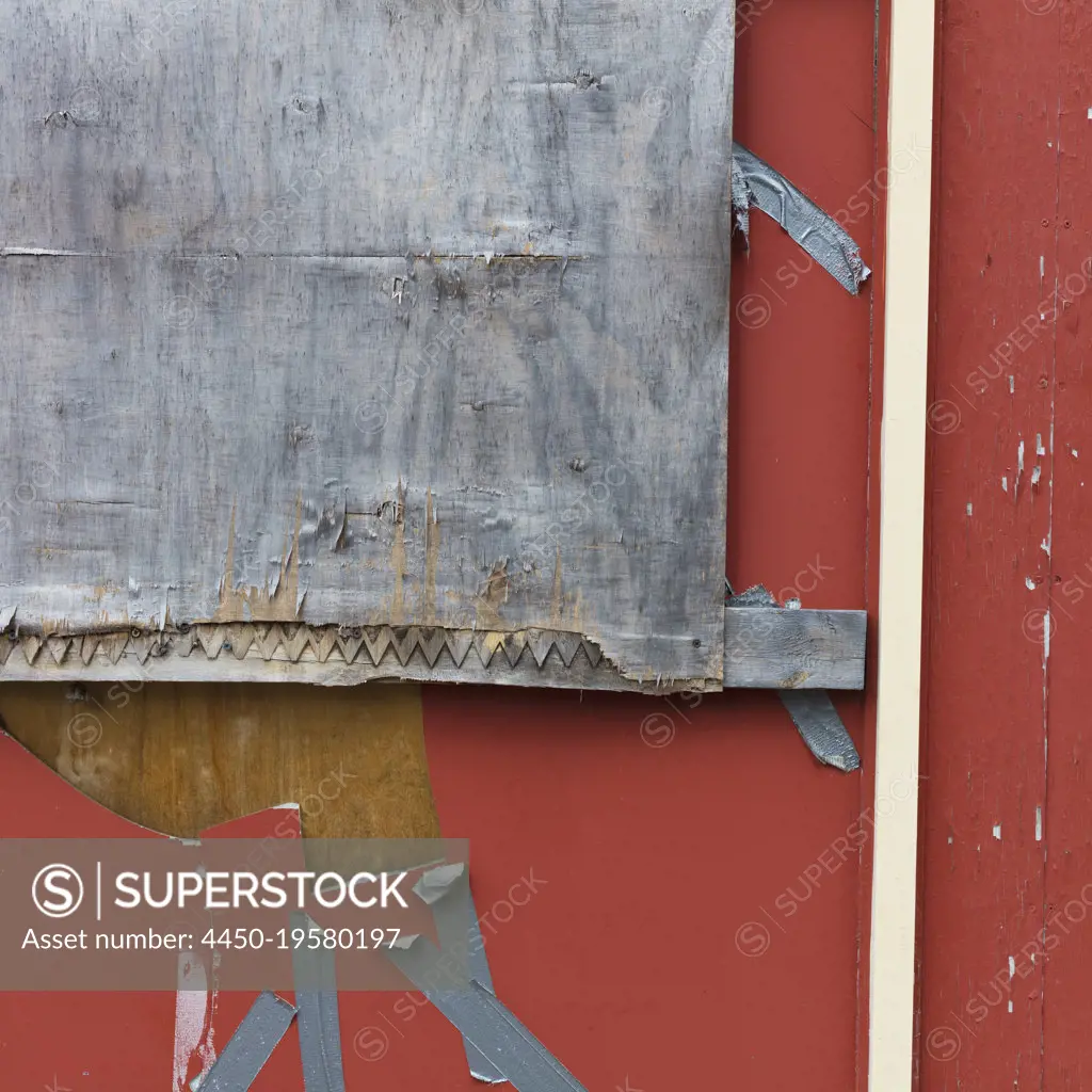 Detail of plywood and duct tape covering the window of an abandoned building