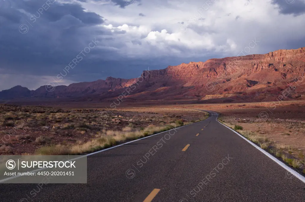 Echo Cliffs, a rock cliff formation of sandstone cliffs rising above a valley in Arizona, sunlight and cloud.