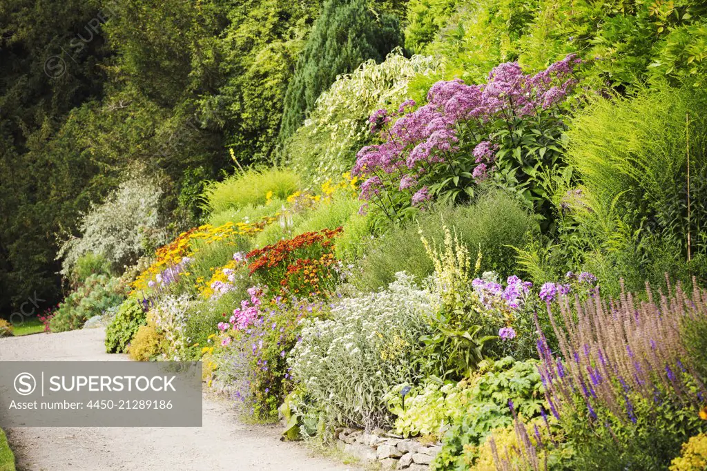 Footpath along a mixed border of flowers at Waterperry Gardens in Oxfordshire.