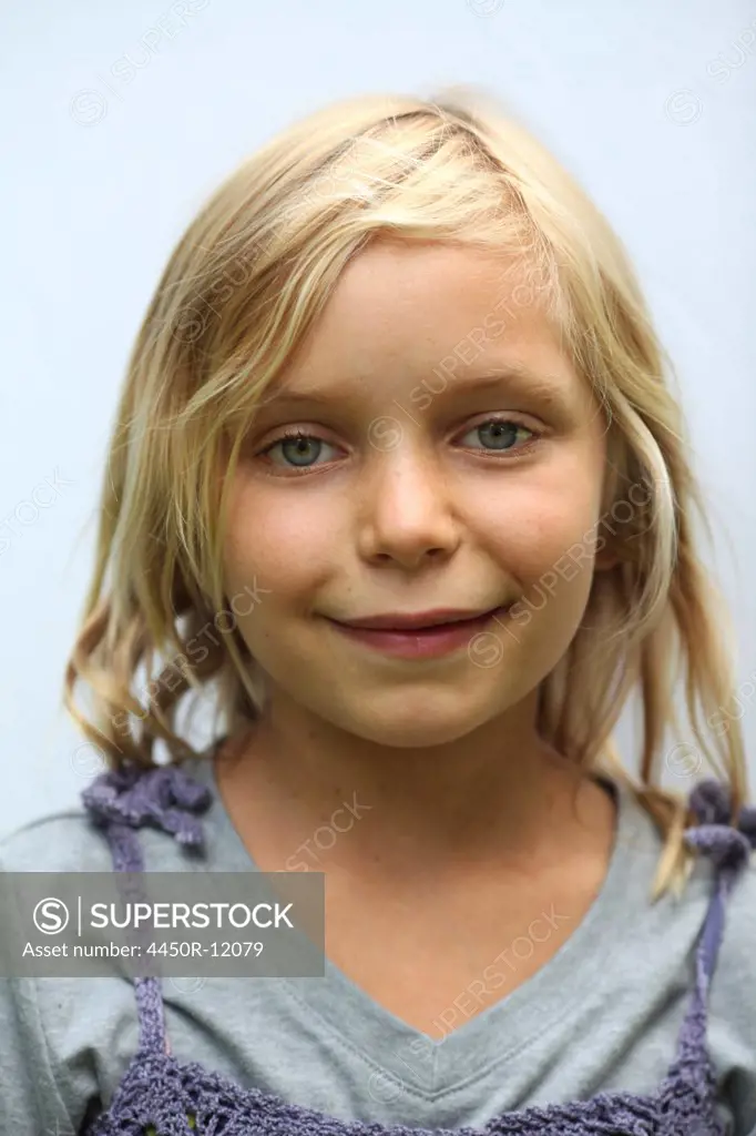 A young girl with blonde hair, and blue eyes. Smiling and looking at the camera.  Woodstock, New York, USA