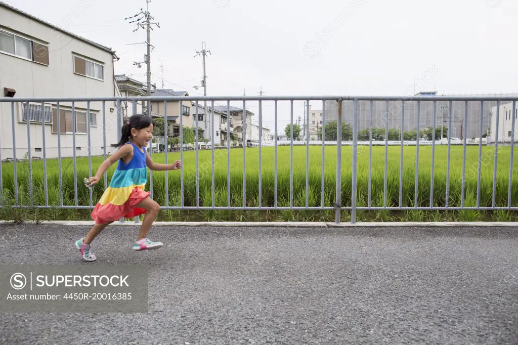 A young girl running along a footpath.