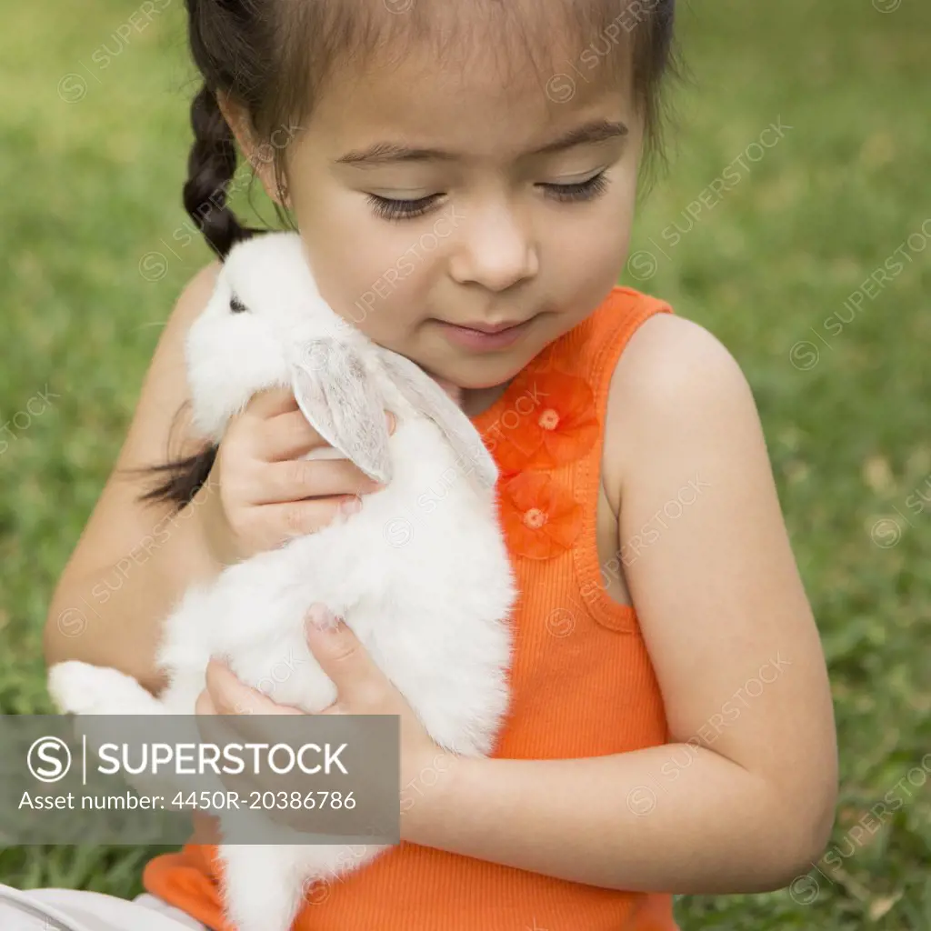 A child holding a large white rabbit.