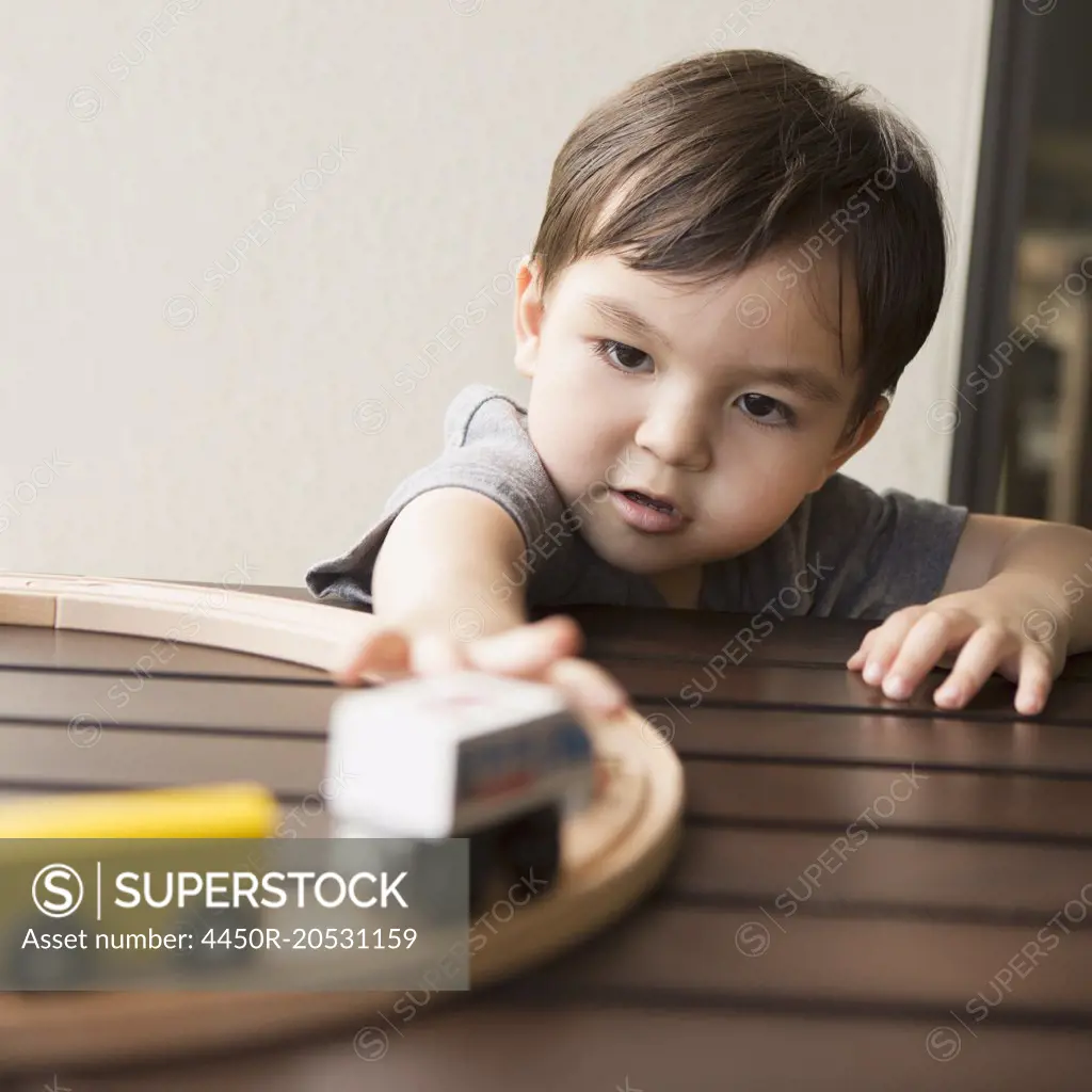 Young boy playing with a wooden train set.