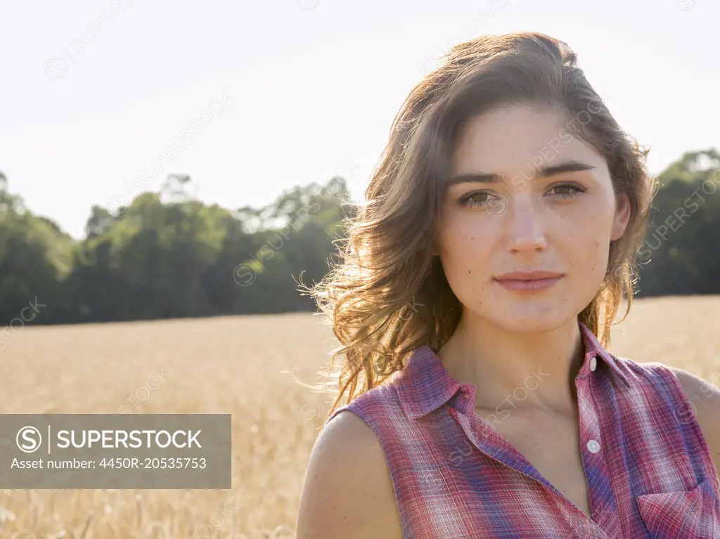 A young woman standing in a field of tall ripe corn.