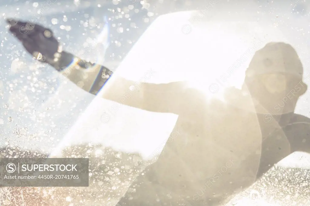 A swimmer in a wet suit running into the water, making a splash.