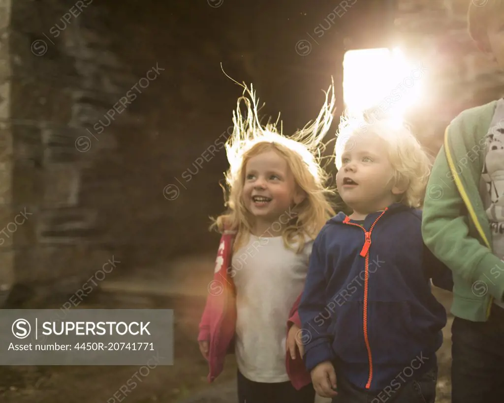 Two children on a farm, looking upwards with curiousity and excitement.