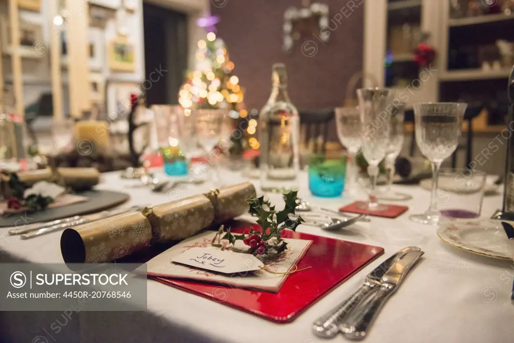 A table laid for a Christmas meal, with silver and crystal glasses and a Christmas tree in the background.