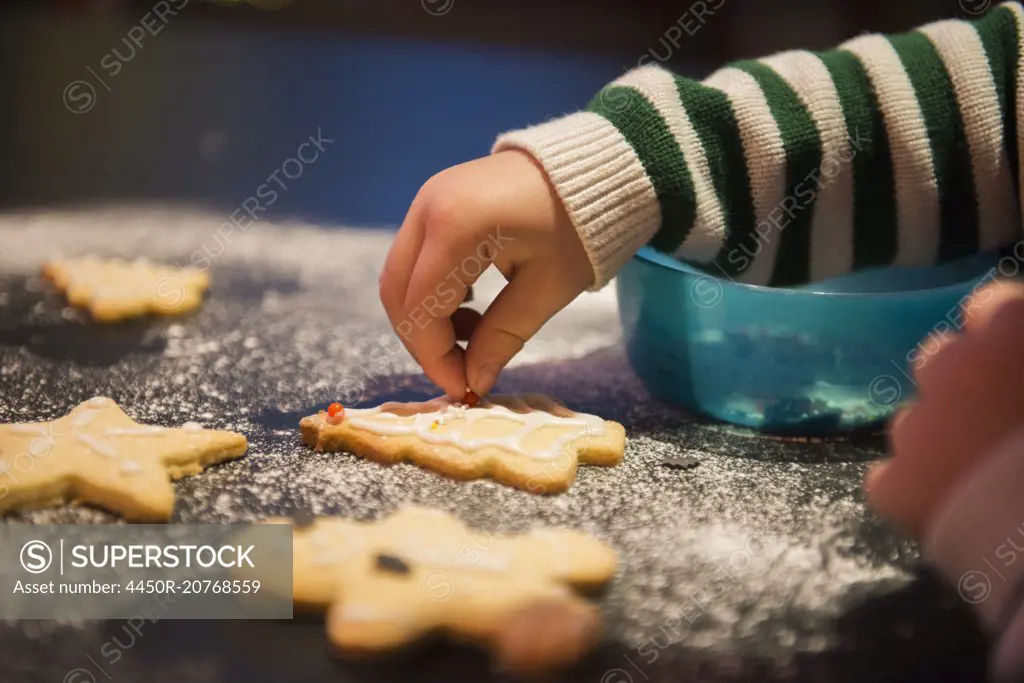 A child decorated Christmas biscuits.