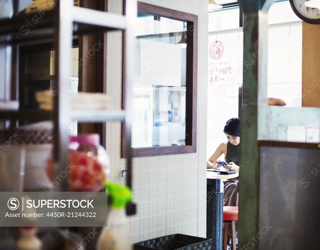 The ramen noodle shop. A woman sitting in a cafe, view through a door.