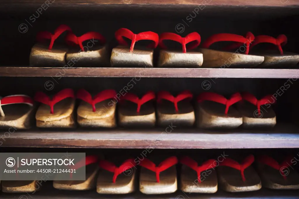 Rows of traditional wooden sandals with thick soles and red straps worn by geisha, okobo or geta.