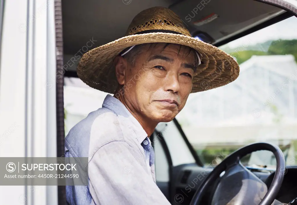 A man in a hat sitting in the driving seat of a truck.