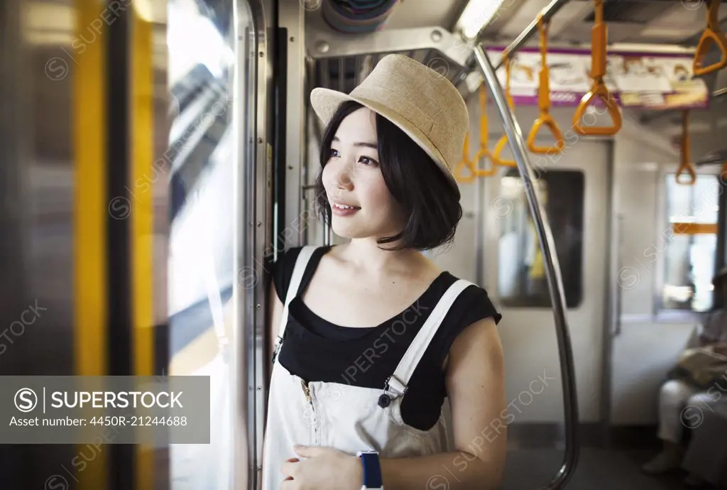 Young woman wearing a hat traveling on a train.