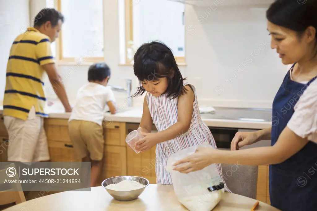 Family home. Two parents and two children preparing a meal.