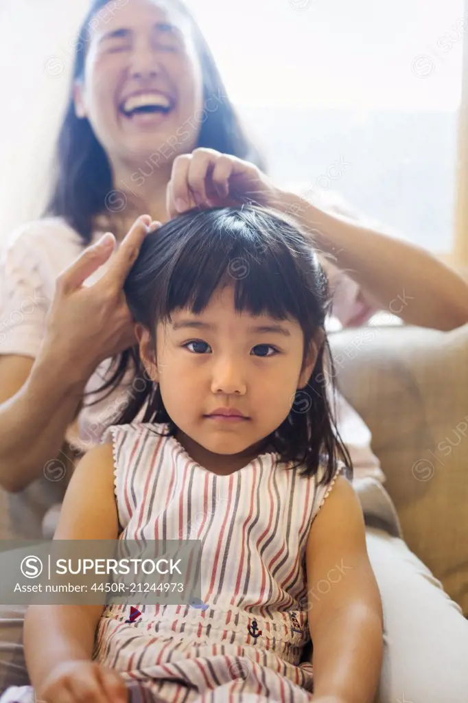 Family home. A mother combing her daughter's hair.