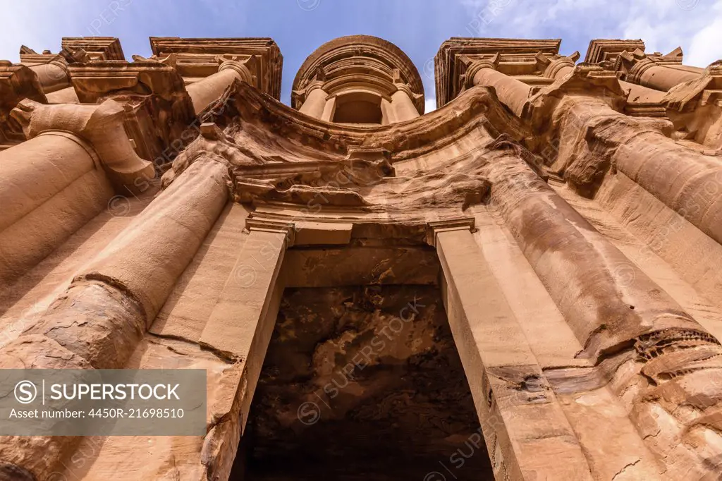 Low angle exterior view of the rock-cut architecture of El Deir or The Monastery at Petra, Jordan.