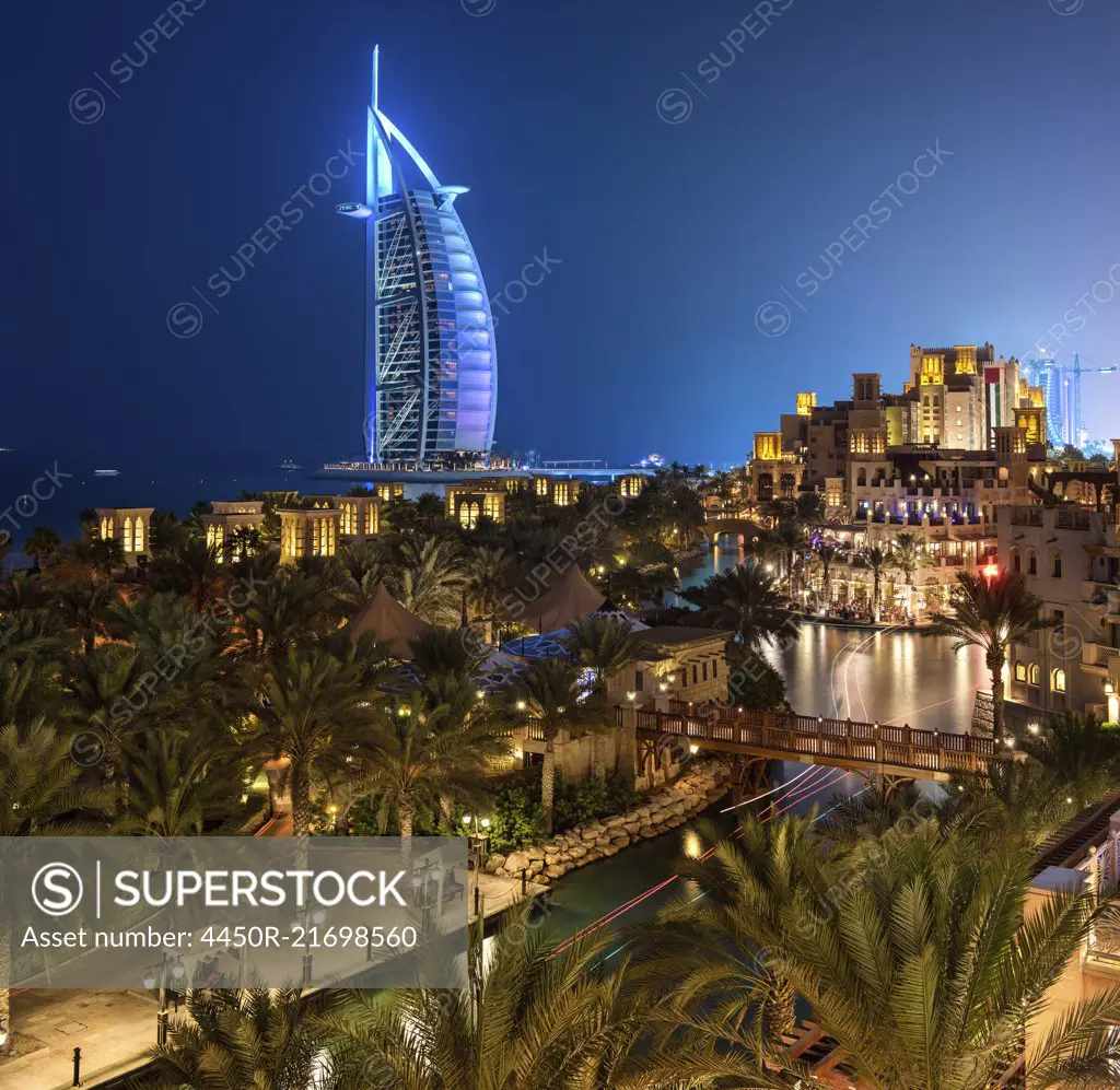 View of illuminated Burj Al Arab skyscraper in Dubai, United Arab Emirates at dusk.