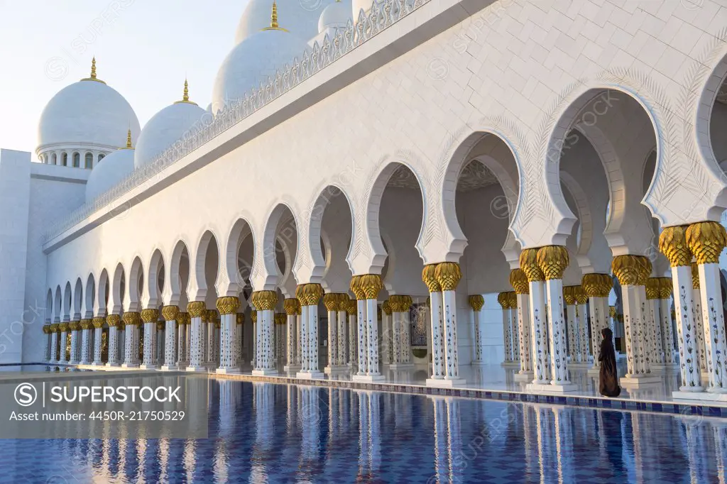 White colonnade of Sheikh Zayed Mosque and blue fountain, Abu Dhabi, United Arab Emirates.