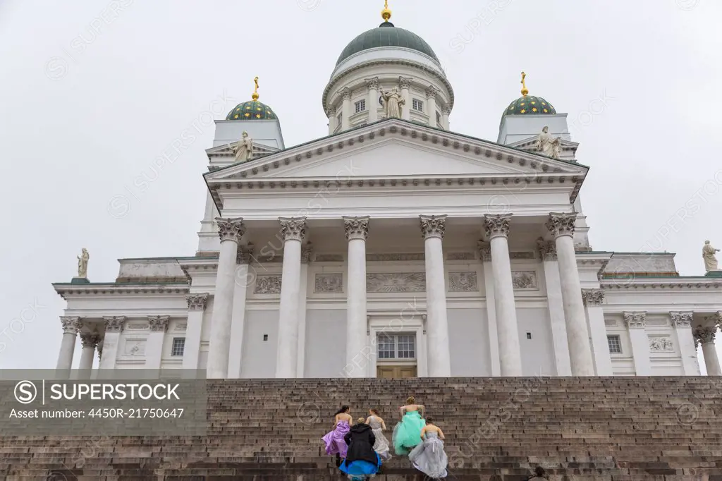 Group of women in colourful dresses walking up the steps of the Lutheran Cathedral in Helsinki, Finland.