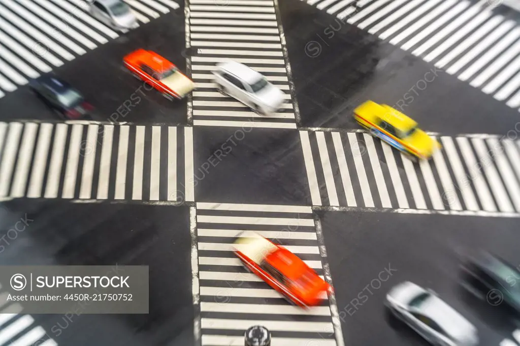 High angle view of cars driving on urban street across pedestrian crossings.