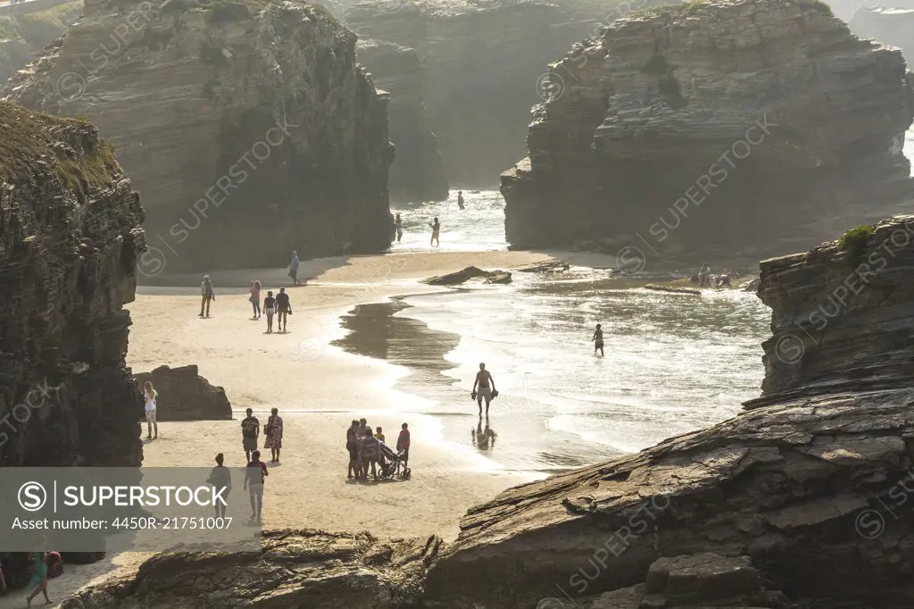 People on sandy beach surrounded by rocks.