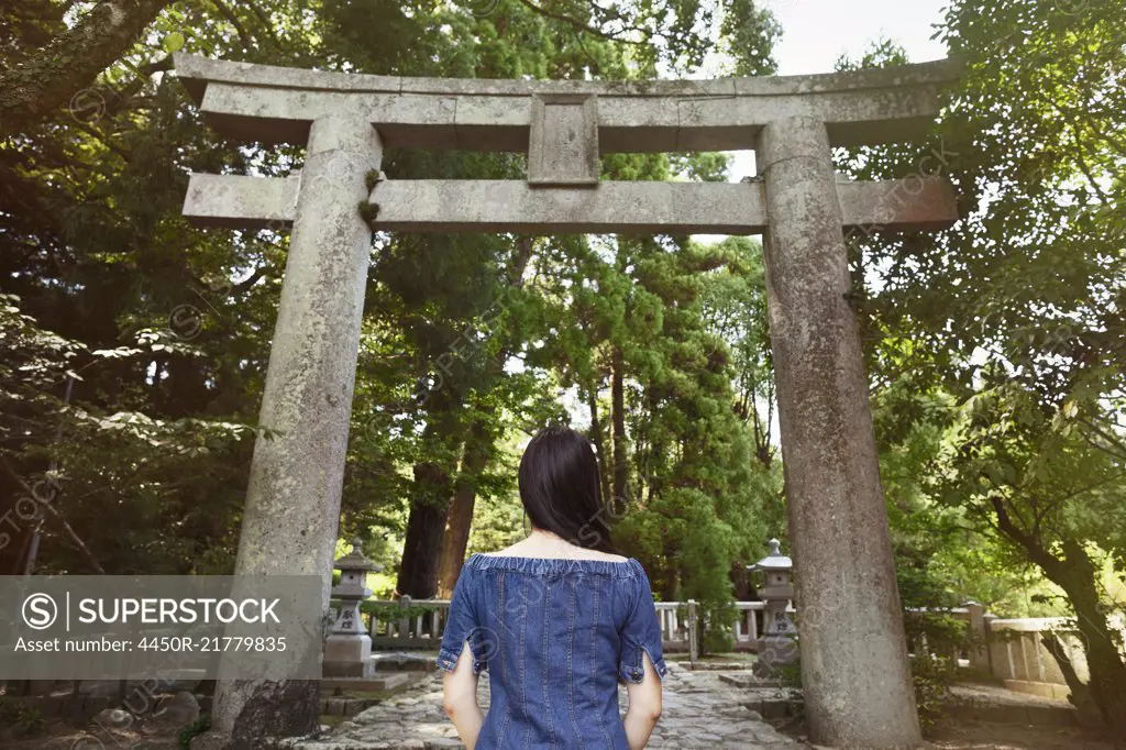 Rear view of young woman wearing blue dress standing at Shinto Sakurai Shrine, Fukuoka, Japan.