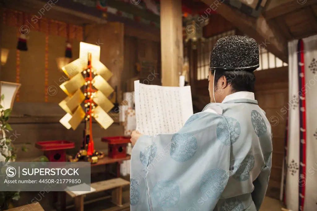 Rear view of priest holding scroll at Shinto Sakurai Shrine, Fukuoka, Japan.