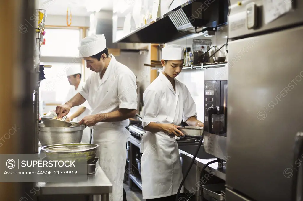 Two chefs working in the kitchen of a Japanese sushi restaurant.