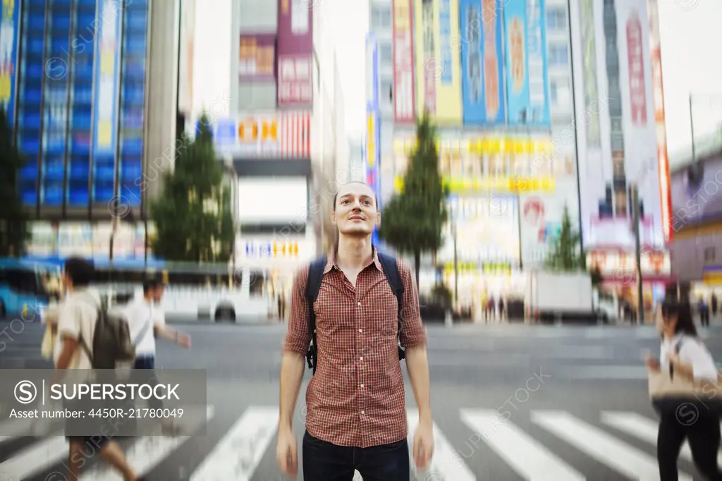 A Western man in Tokyo on the street, looking around him. Long exposure, blurred background effect.