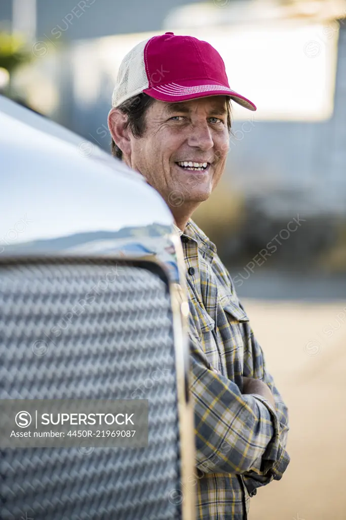 Caucasian man truck driver with his truck parked in a lot at a truck stop.