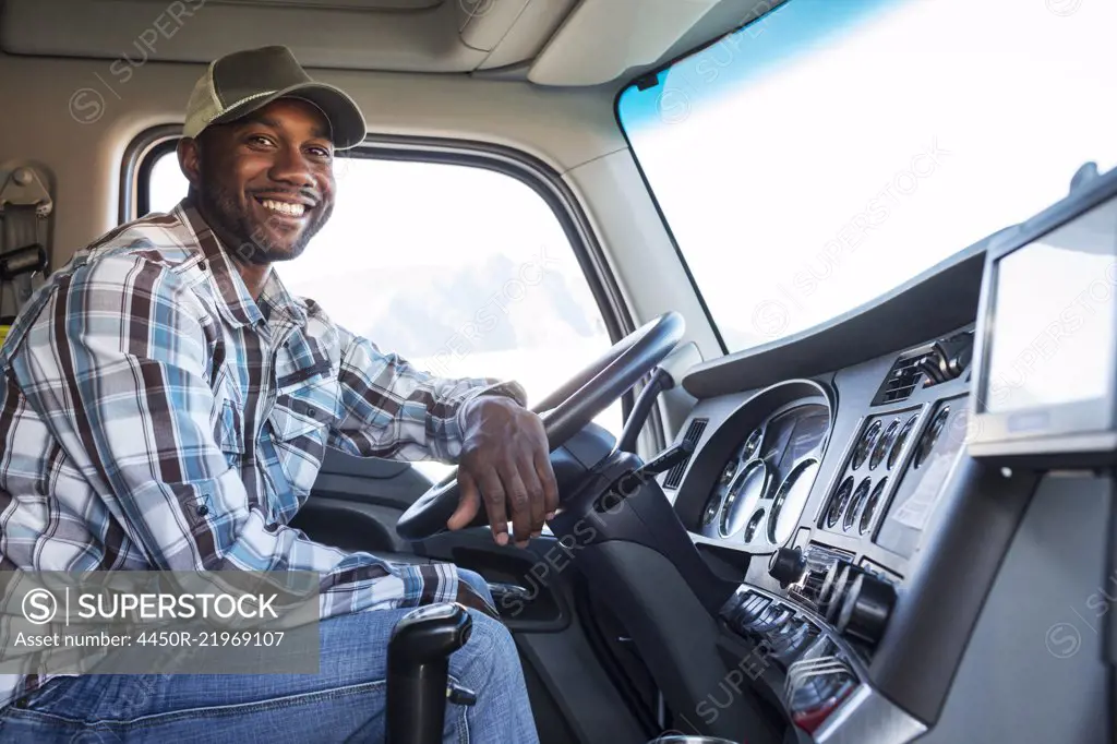 Black man truck driver in the cab of his commercial truck.