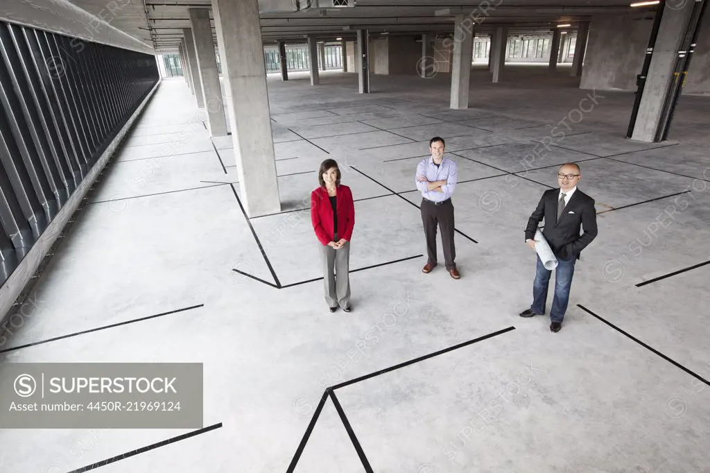 Asian architect with Caucasian man and woman business people in a new raw business space.