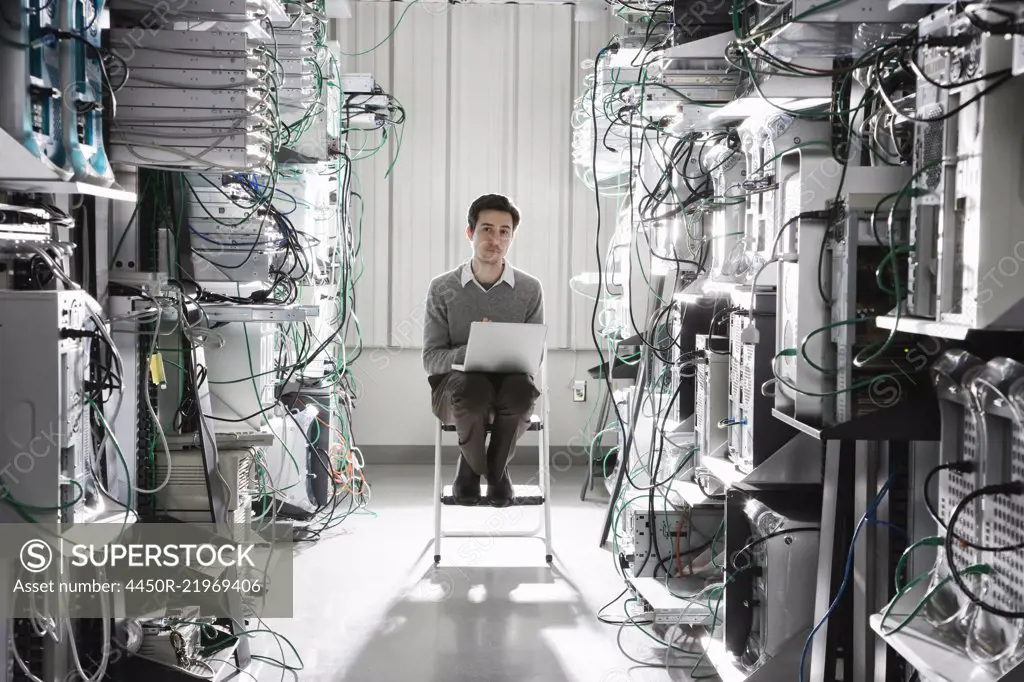 Caucasian male technician working on computer servers in a computer server farm.