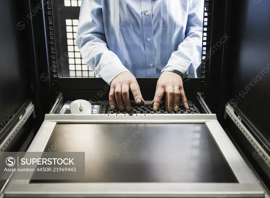 Closeup of a the hands of a technician working on data from a computer server farm.