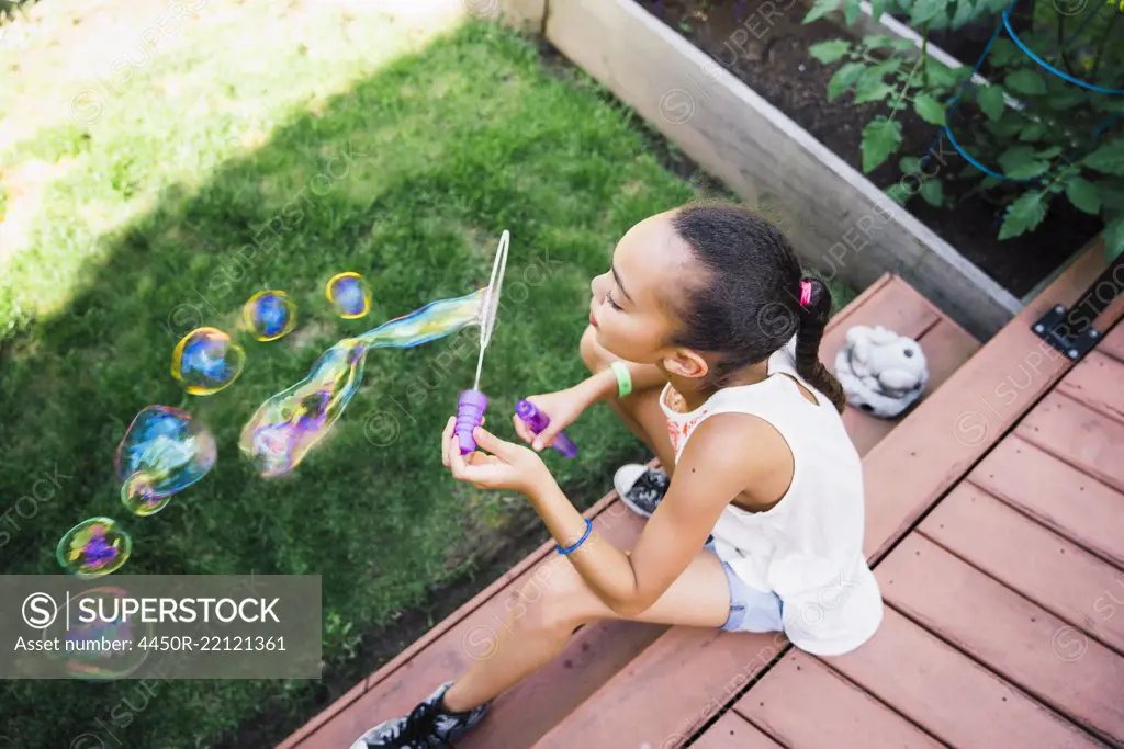 Tween Girl Blowing Bubbles in the Backyard