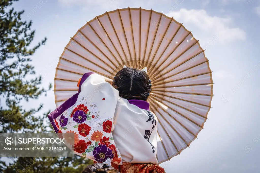 Japanese girl carrying traditional umbrella during a spring festival.