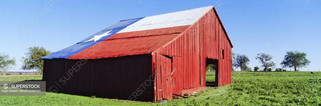 Red Barn in Field With Texas Flag on Roof