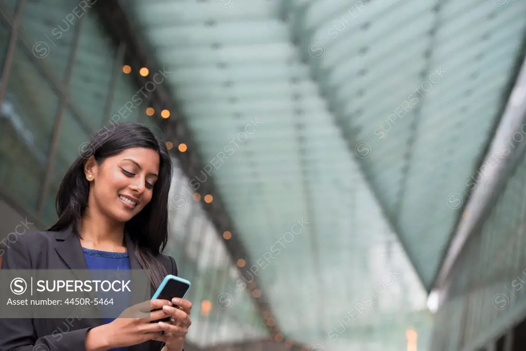 Business people out and about in the city. A young woman in a blue dress and grey jacket.