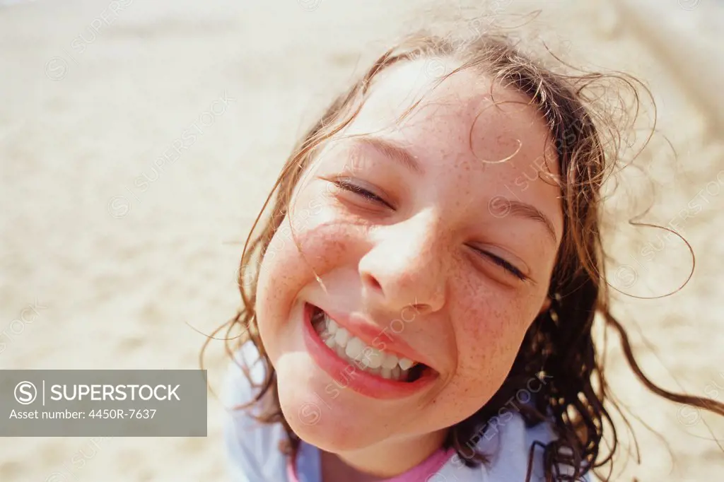 A young girl with a wide grin eyes half closed and wet hair