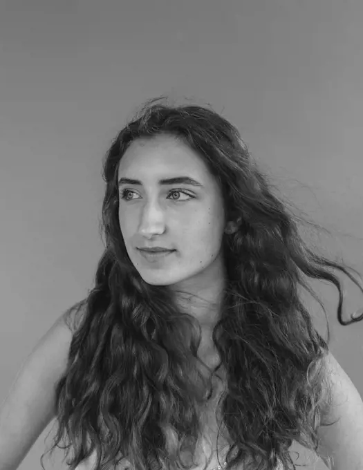 Black and white portrait of pretty sixteen year old girl, wind blowing her long wavy hair