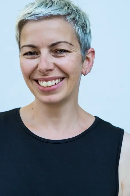 Woman with short grey hair wearing black top smiling at camera.