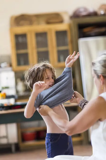 mother helping her 5 year old boy to get dressed