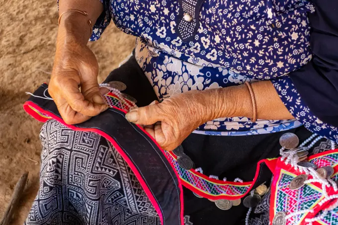 Woman seated stitching, making traditional garments, Vang Vieng, Laos